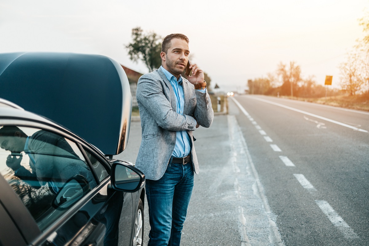 Elegant middle age business man calling towing service for help Man waiting on side of road for tow truck